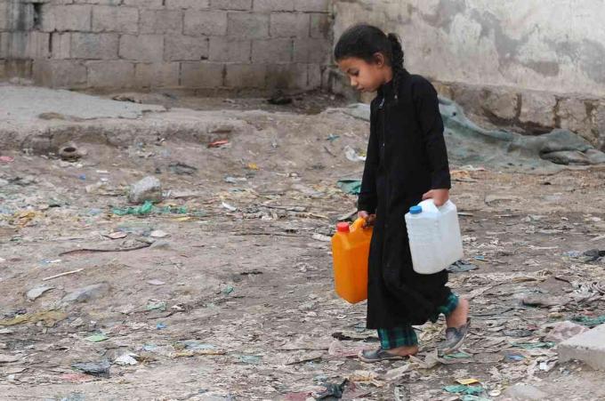 Ein kleines Mädchen trägt während einer anhaltenden Krise um sauberes Wasser im Jemen mit sauberem Wasser gefüllte Kanister