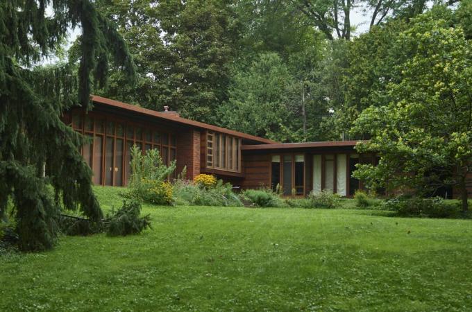 kleines, ranchartiges horizontales modernes Haus aus vertikalem Glas und Holz in einer verworrenen Umgebung