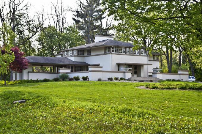 lange Aufnahme von grauem Haus, dunklen Walmdächern, horizontaler Ausrichtung, Wänden und Flügeln, riesigem Mittelschornstein im Hauptteil des Hauses