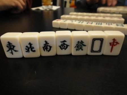 Die Winde und Drachen kacheln in einem Mahjong-Set aufrecht auf einem Tisch.