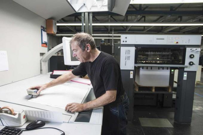 Arbeiter, der digitale Druckgeräte in der Druckwerkstatt vorbereitet