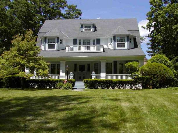 Großes weißes Haus mit riesigem grauem Dach und großem, grünem Rasen