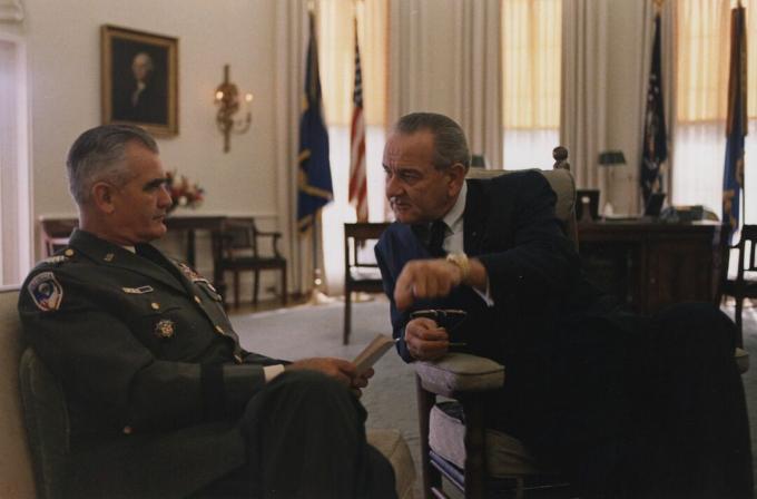 General William Westmoreland in Uniform der US-Armee und sitzend spricht mit Präsident Lyndon B. Johnson im Oval Office.