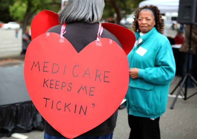 Frau trägt ein herzförmiges Schild mit der Aufschrift „Medicare Keeps Me Ticking“