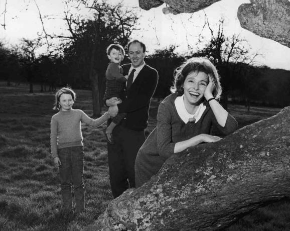 Schwarzweißfoto von Roald Dahl, der seine Kinder hält; seine Frau Patricia Neal stützt sich auf einen Baum