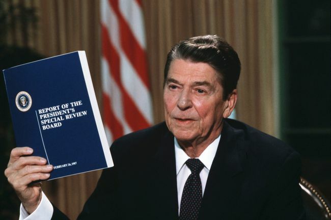 Präsident Ronald Reagan hält eine Kopie des Berichts der Tower Commission über den Iran-Contra-Skandal