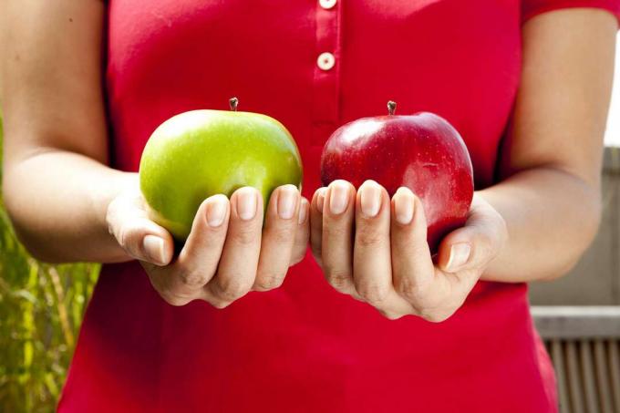Person, die grüne und rote Äpfel hält