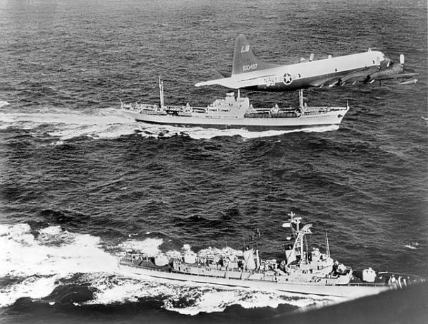 Der sowjetische Frachter Anosov, hinten, wird von einem Marineflugzeug und dem Zerstörer USS Barry eskortiert, während er Kuba während der Kubakrise von 1962 verlässt.