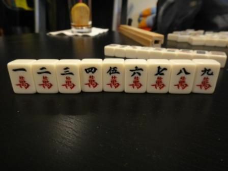 Der Charakteranzug einer Reihe von Mahjong-Kacheln, die auf einem Tisch sitzen.