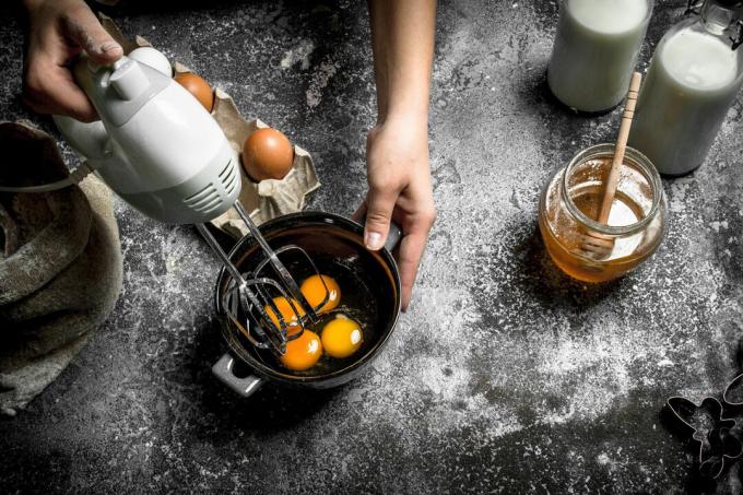 Person, die Eier auf einem Tisch mit Milch und Honig schlägt