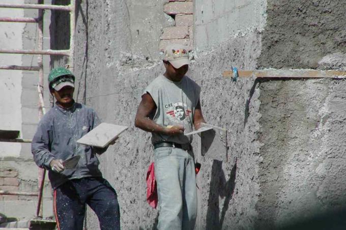 zwei Arbeiter tragen eine Schicht Gips mit Kellen auf