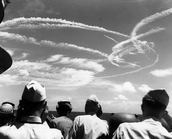 Amerikanische Seeleute blicken gen Himmel auf die Kondensstreifen, die von Flugzeugen gebildet werden, die um die Flotte kämpfen.