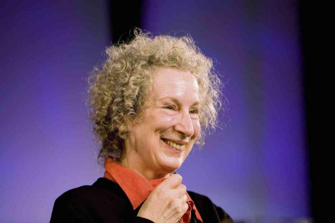 Bild von Margaret Atwood, die gegen einen lila Hintergrund lächelt